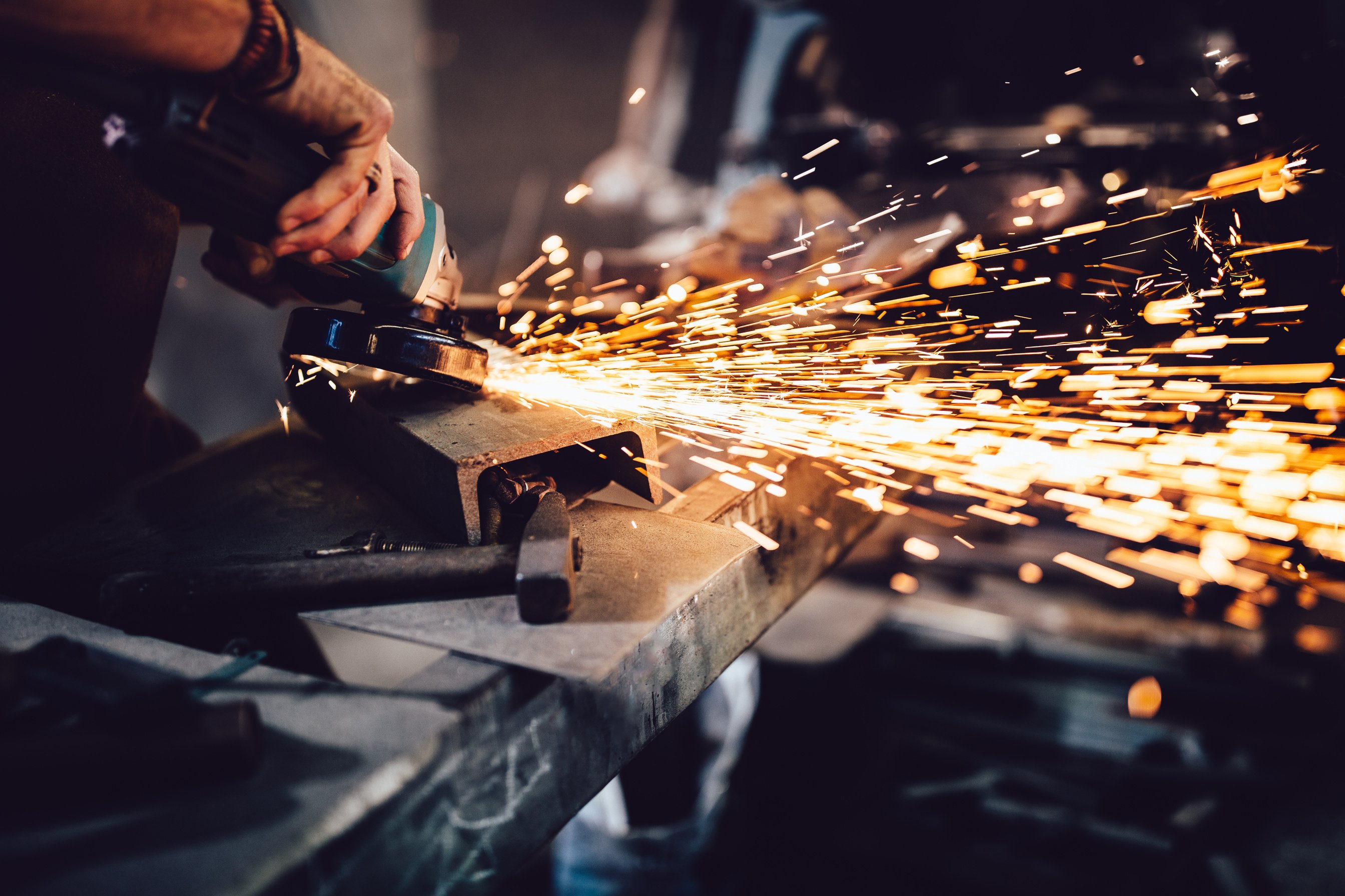 Blacksmith working with power tools and metals in workshop